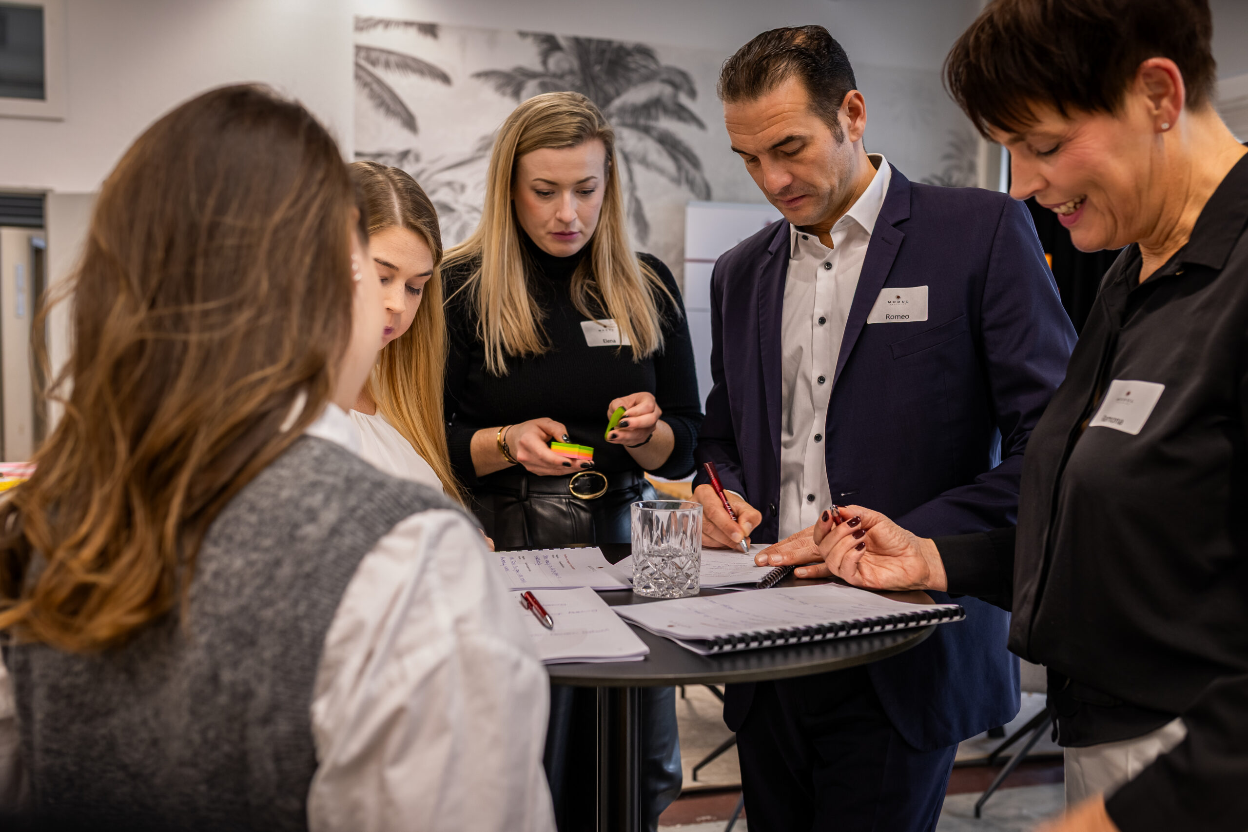 Teilnehmende arbeiten gemeinsam mit Notizen am Stehtisch – MODUL TRAINING