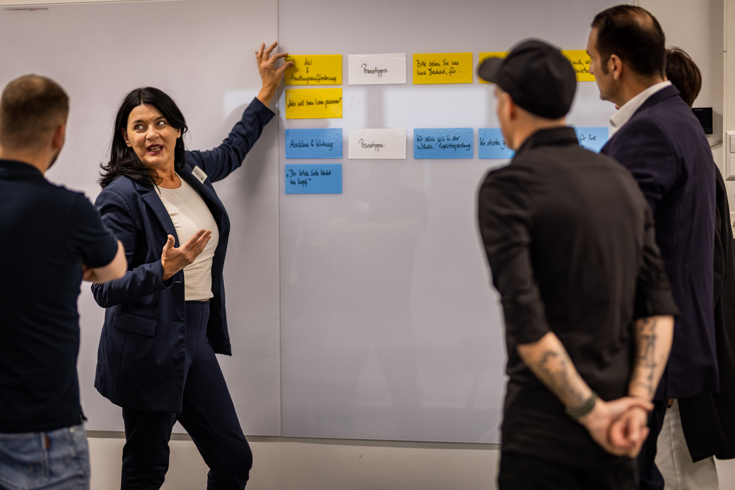 Seminarleitung strukturiert mit dem Projektteam Karten an der Whiteboard-Wand – MODUL TRAINING