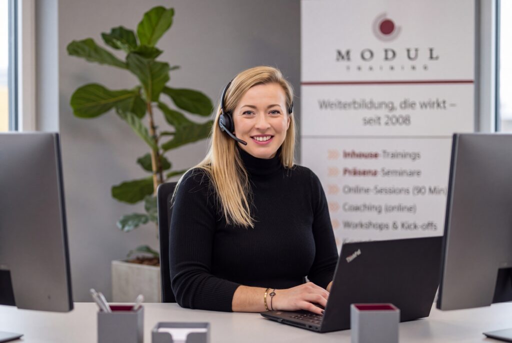 Elena Etzrodt, Ansprechpartnerin für Inhouse-Seminare bei MODUL TRAINING, am Schreibtisch mit Headset