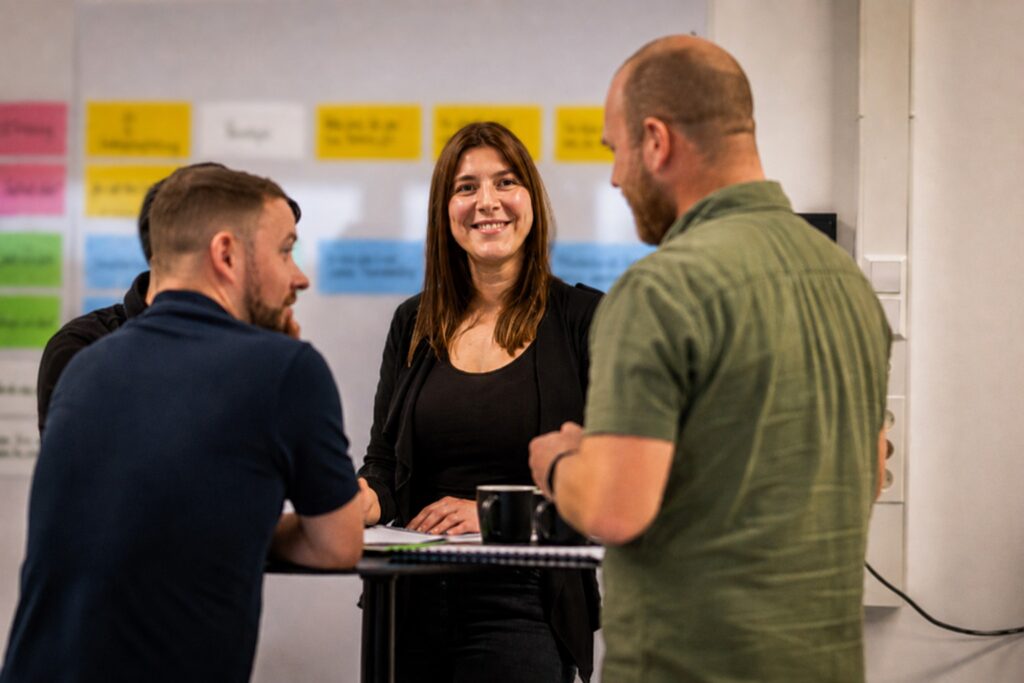 Neue Führungskraft im Gespräch mit dem Team vor einer Ideenwand – MODUL TRAINING