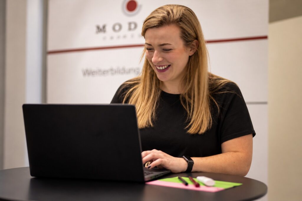 E-Mail-Kommunikation: Mitarbeiterin verfasst konzentriert eine E-Mail am Laptop – MODUL TRAINING