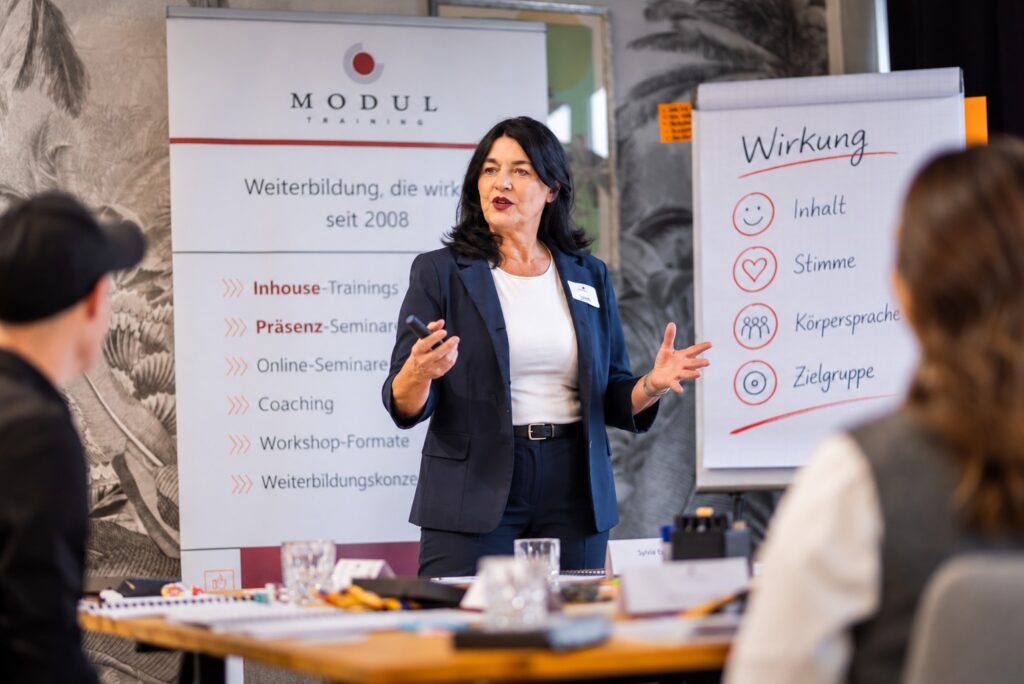 Rhetorik Seminar: Seminarleitung erläutert am Flipchart die Wirkungsfaktoren Inhalt, Stimme und Körpersprache – MODUL TRAINING