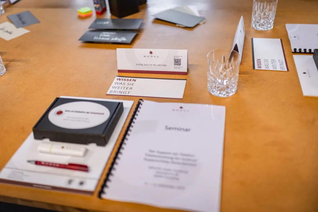 Vorbereiteter Seminartisch mit Seminarbox, Workbook, Namensschild und Moderationsmaterial