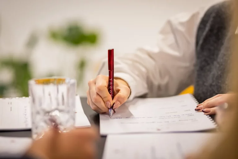 Teilnehmerin notiert Erkenntnisse mit einem MODUL-Kugelschreiber im Seminar-Workbook