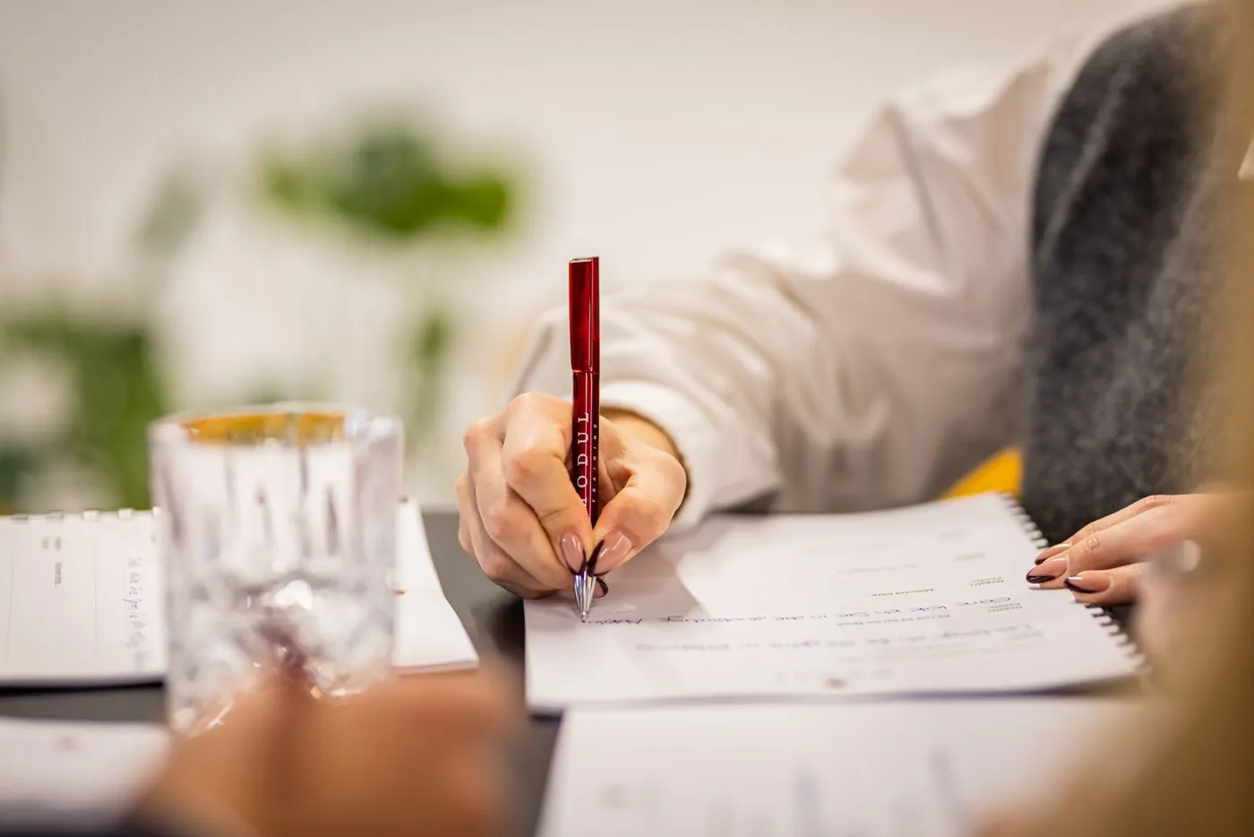 Teilnehmerin notiert Erkenntnisse mit einem MODUL-Kugelschreiber im Seminar-Workbook