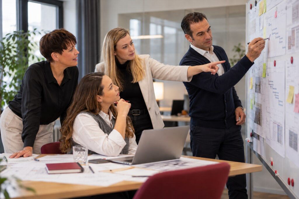 Projekte umsetzen und absichern: Projektteam prüft den Plan am Whiteboard – MODUL TRAINING