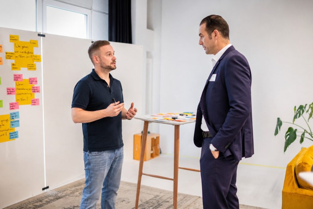 Zwei Personen klären ein schwieriges Thema ruhig vor der Moderationswand – MODUL TRAINING