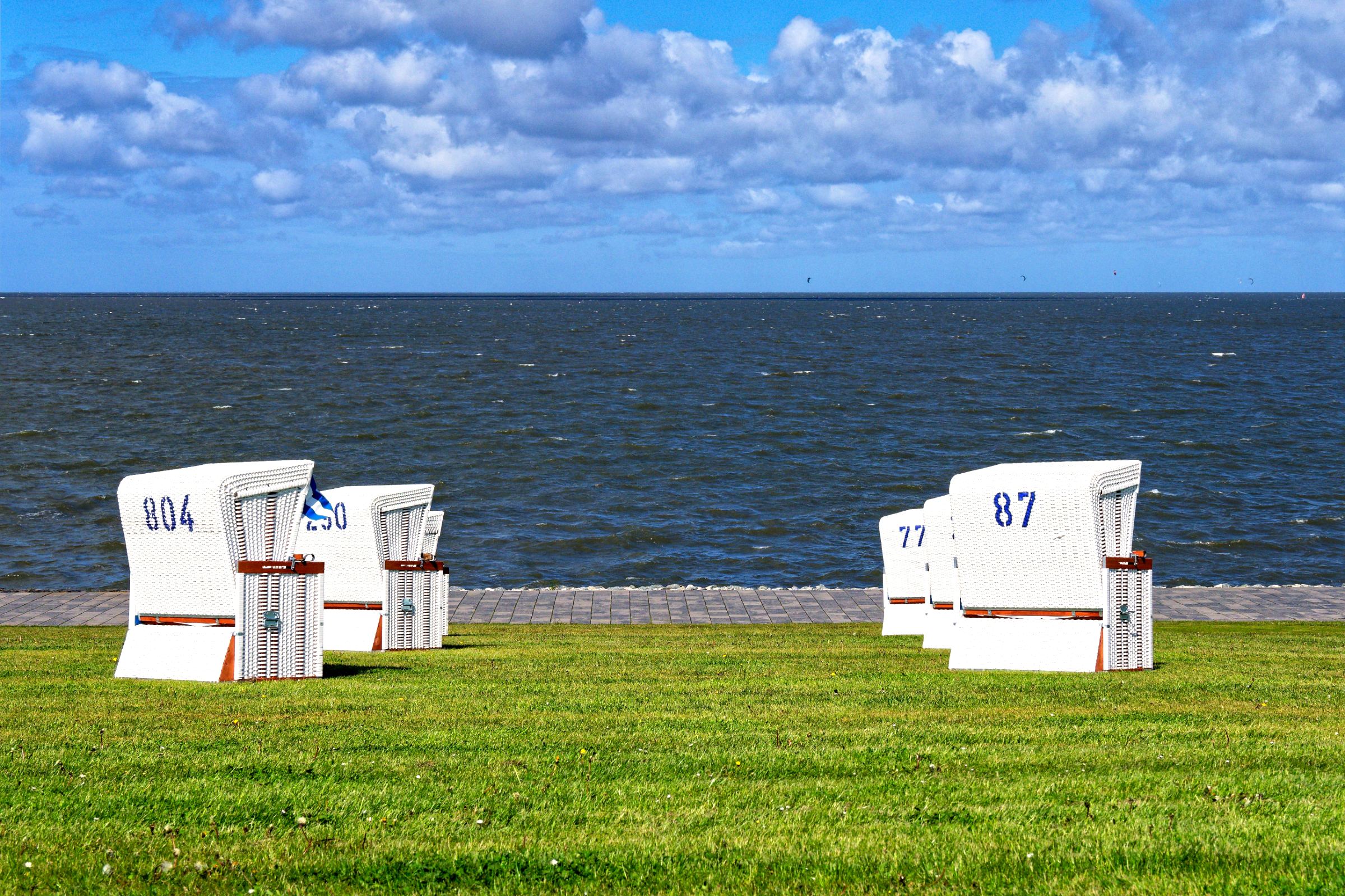 Sommerakademie an der Nordsee: weiße Strandkörbe auf dem Deich vor dem Meer