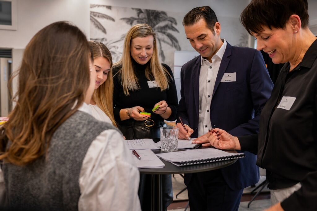 Team stimmt sich gemeinsam am Stehtisch ab – MODUL TRAINING
